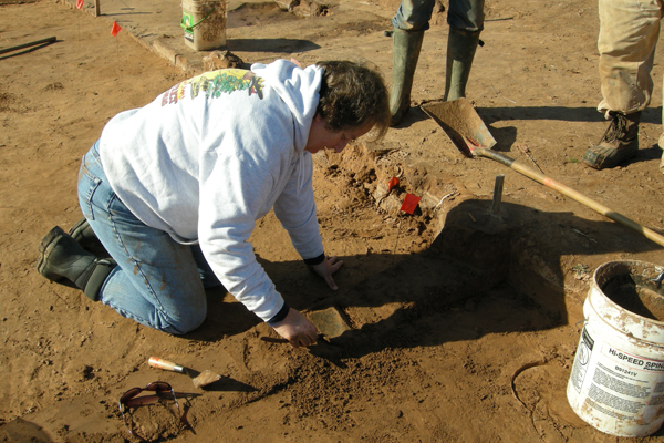 Mary Brennan excavating sherd on House 2 floor