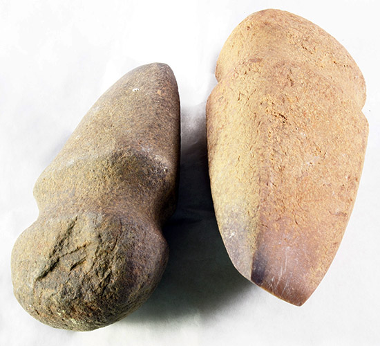 Closeup photo of two grooved stone axes against a plain white background. 