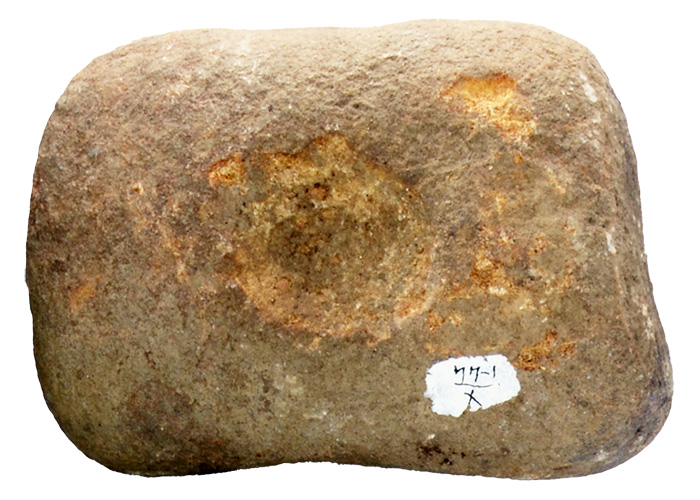 Photo of a pale yellowish brown stone with a round indention in the center for placing nuts to be cracked.
