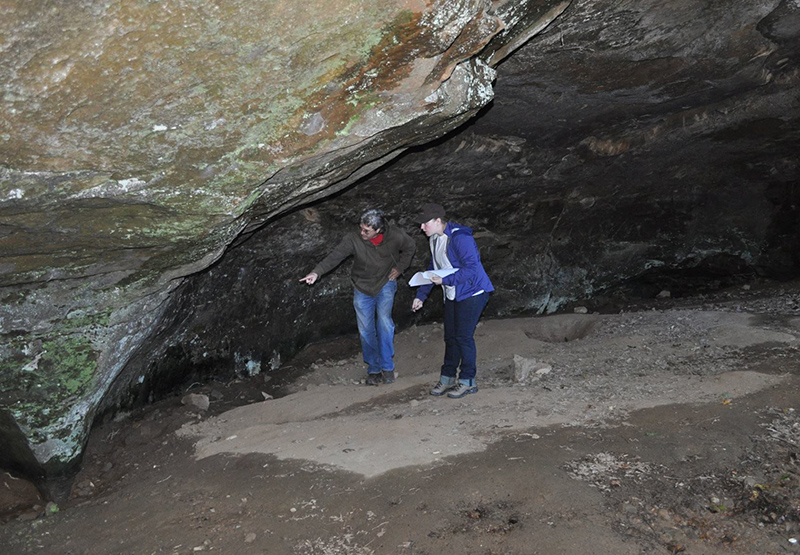 Archeologist Jerry Hilliard pointing out rock art at a bluff shelter site in Arkansas