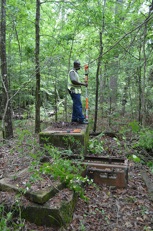 UAM student Mark Abban holding the stadia rod during the total station mapping project. 