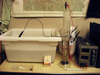 Figure 1. ARAS electrolysis tanks with power supply at right. In front are pH test strips to ensure solution stays strongly alkaline