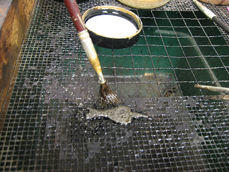 Figure 5. Tannic acid being painted onto trigger guard fragment to prevent deterioration. 