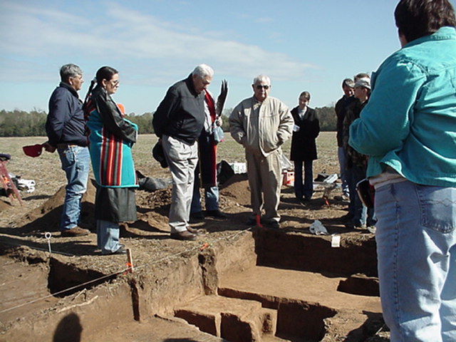 John Berry (behind Jess McKibben) holding eagle feather fan and giving a cedar smoke blessing to archeologists and Quapaws at Wallace Bottom, November 2003.