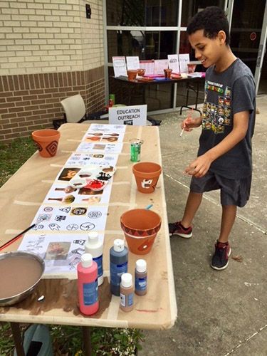 A participant at the Arkansas Archeological Survey's UA Fayetteville Research Station paints pottery that will be used as education outreach tools .