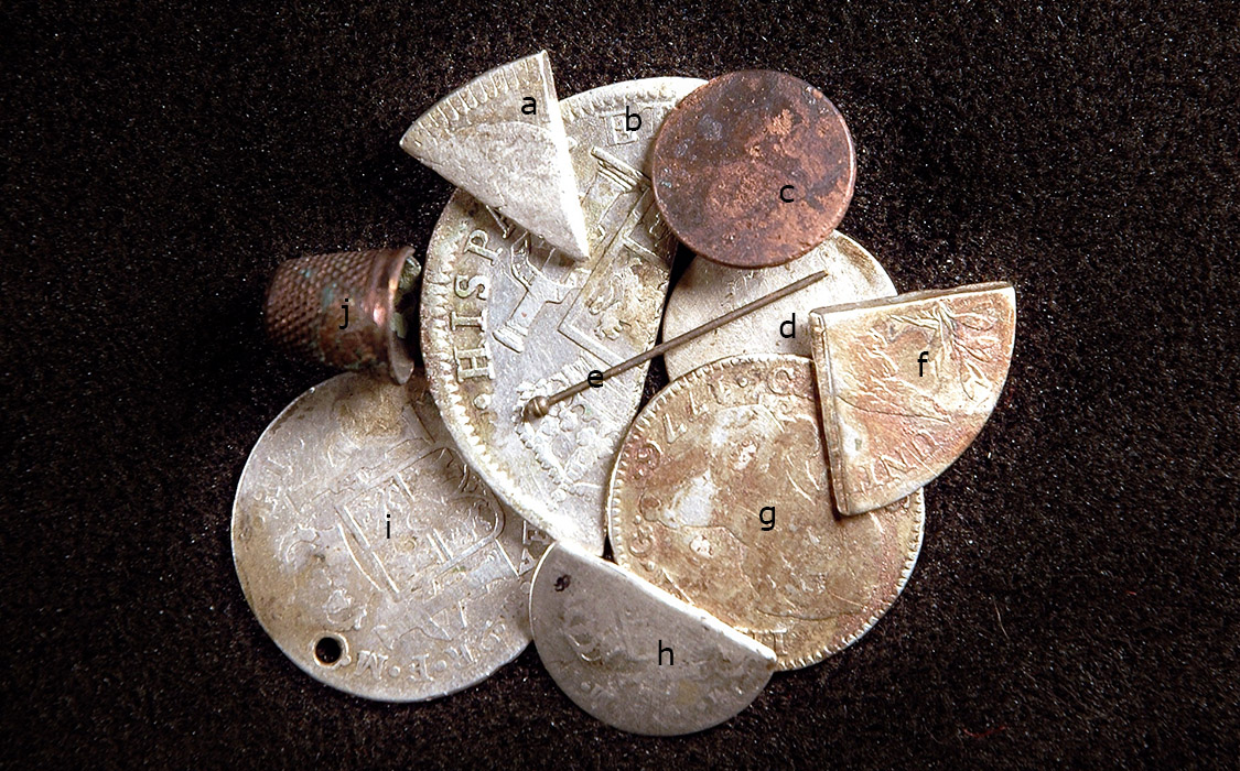 Figure 3. Selected contents of a small leather pouch after metal conservation: (clockwise from upper left) a. 1 bit cut from a Spanish 8 real coin (silver); b. Spanish Charles IV 8 real cut in half (silver); c. copper button with shank; d. US dime, 1798–1807 (silver); e. brass straight pin; f. cut quarter of a US 1808–1836 half dollar (silver); g. Spanish Charles III 2 real coin, 1776 (silver); h. Spanish 1 real coin cut in half (silver); i. perforated Spanish Charles IV? 2 real portrait coin 1789 (silver); and j. a copper thimble.