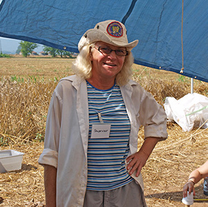 Daytime photo of Marilyn Knapp posing under a sunshade at an archeological excavation site.