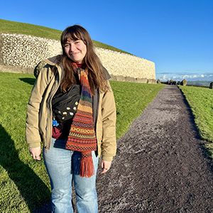 A young woman standing in front of a prehistoric monument.