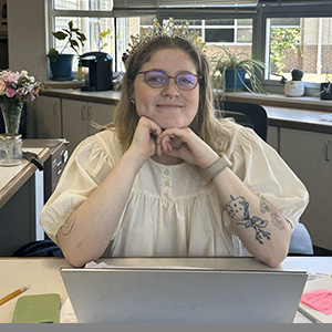 A woman sits at a desk in front of a laptop computer. 