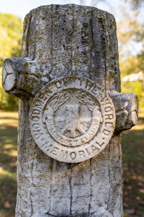 A moss-covered marble monument shaped like a tree stub.